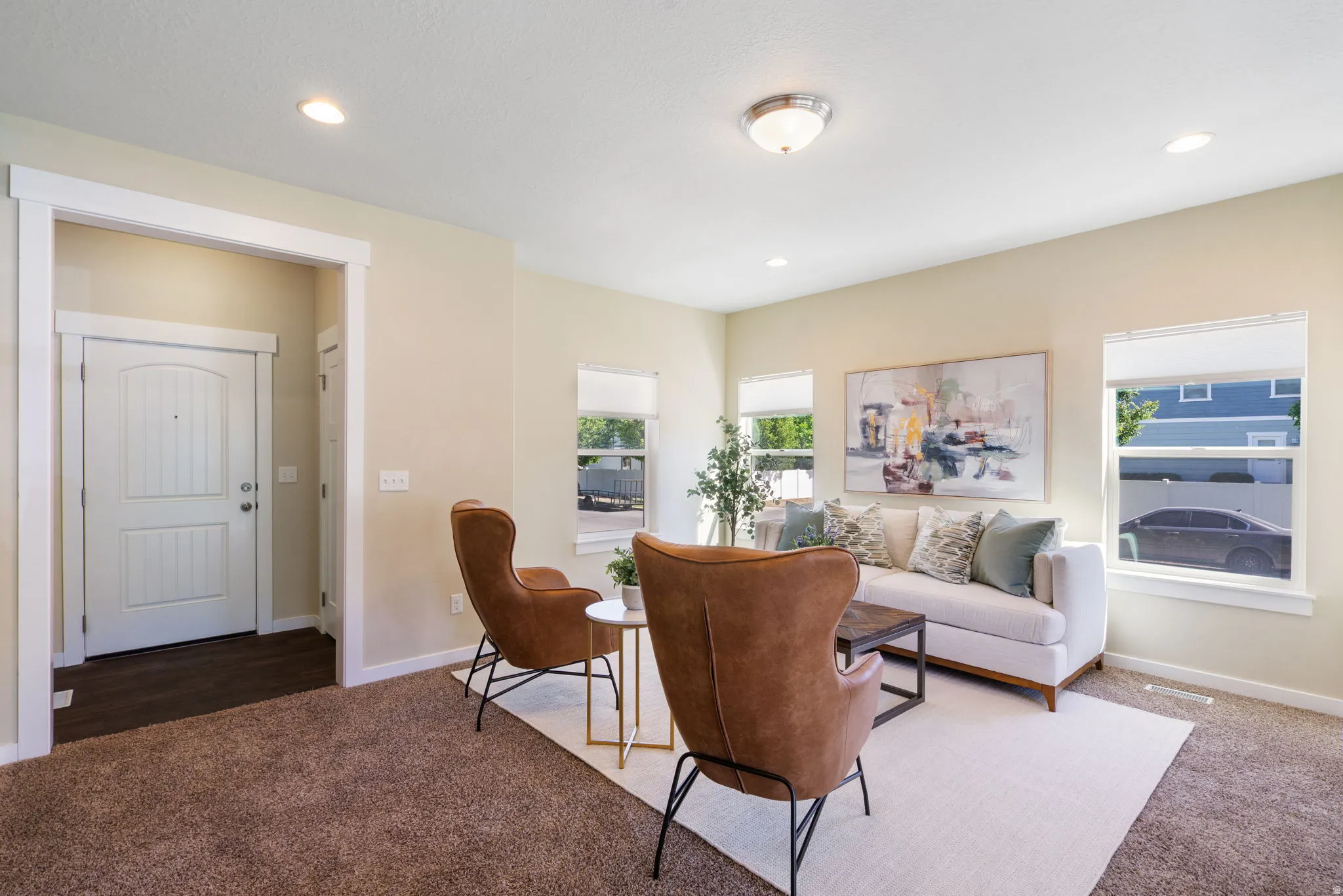 Spacious living area featuring neutral wall tones, recessed lighting, and multiple windows