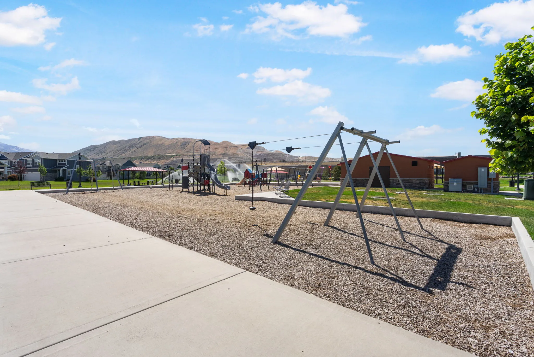 Expansive recreational area featuring a swing set, playground equipment with slides, and a covered picnic structure