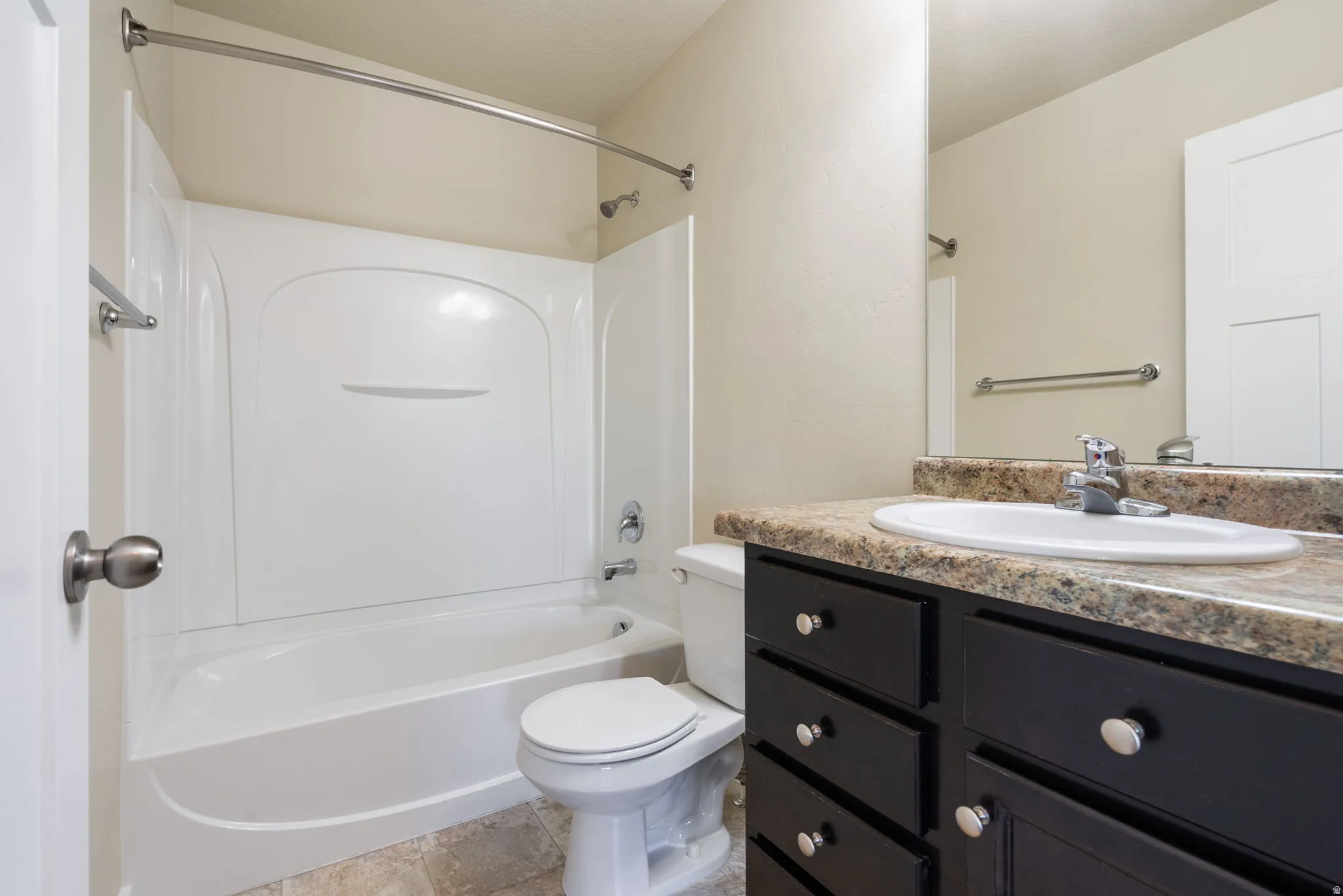 Bathroom featuring a white tub/shower combination, dark wood-finish vanity with a light-colored countertop, and a built-in mirror