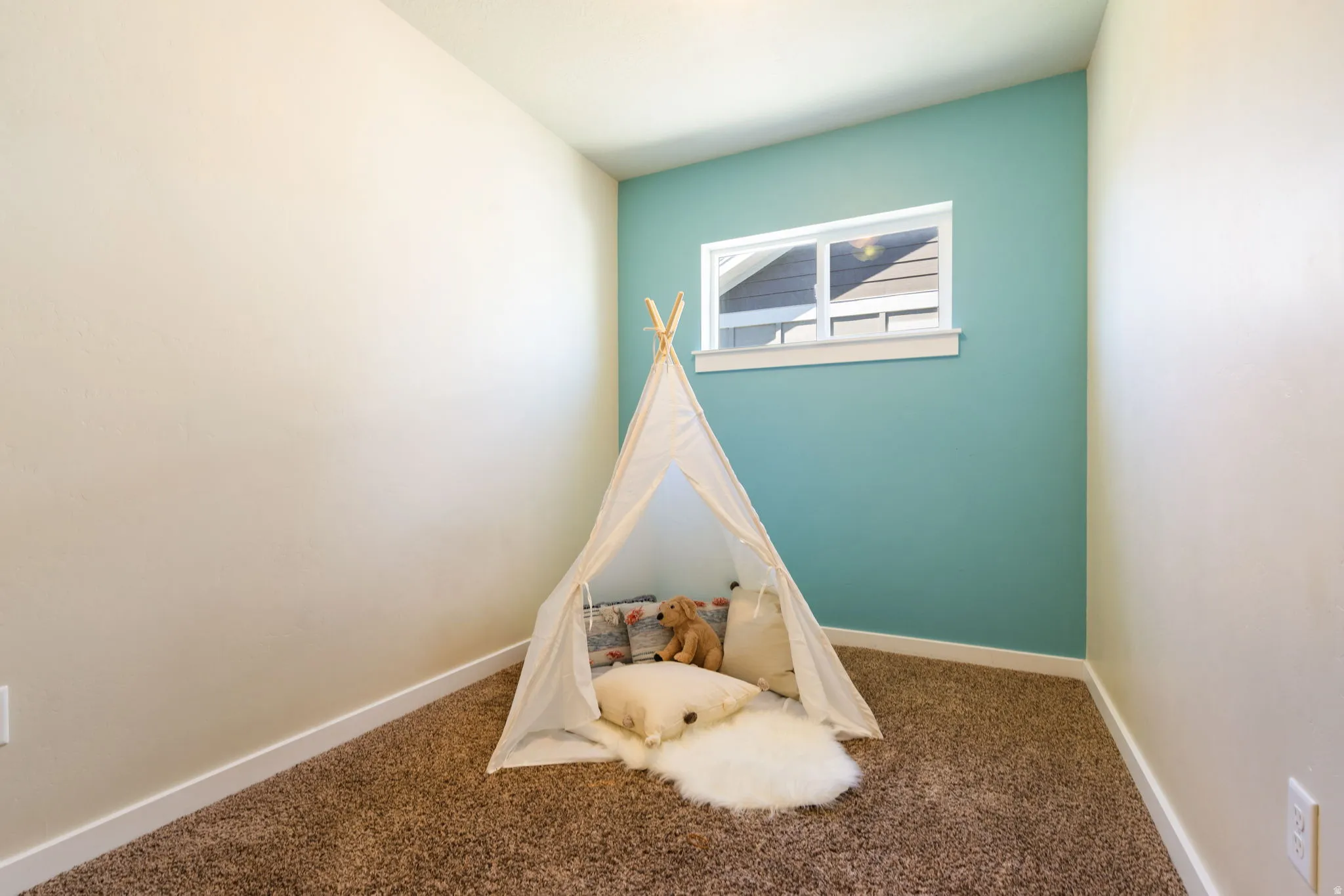 Interior room featuring a window with white trim, a feature wall in a vibrant hue, and neutral walls