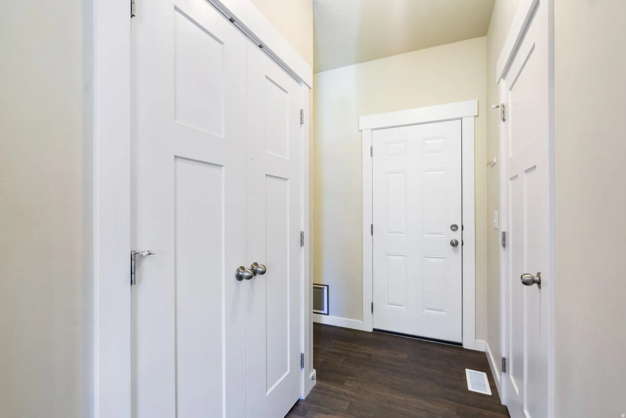 Entryway featuring wood-finish flooring, white panel doors, and neutral wall tones