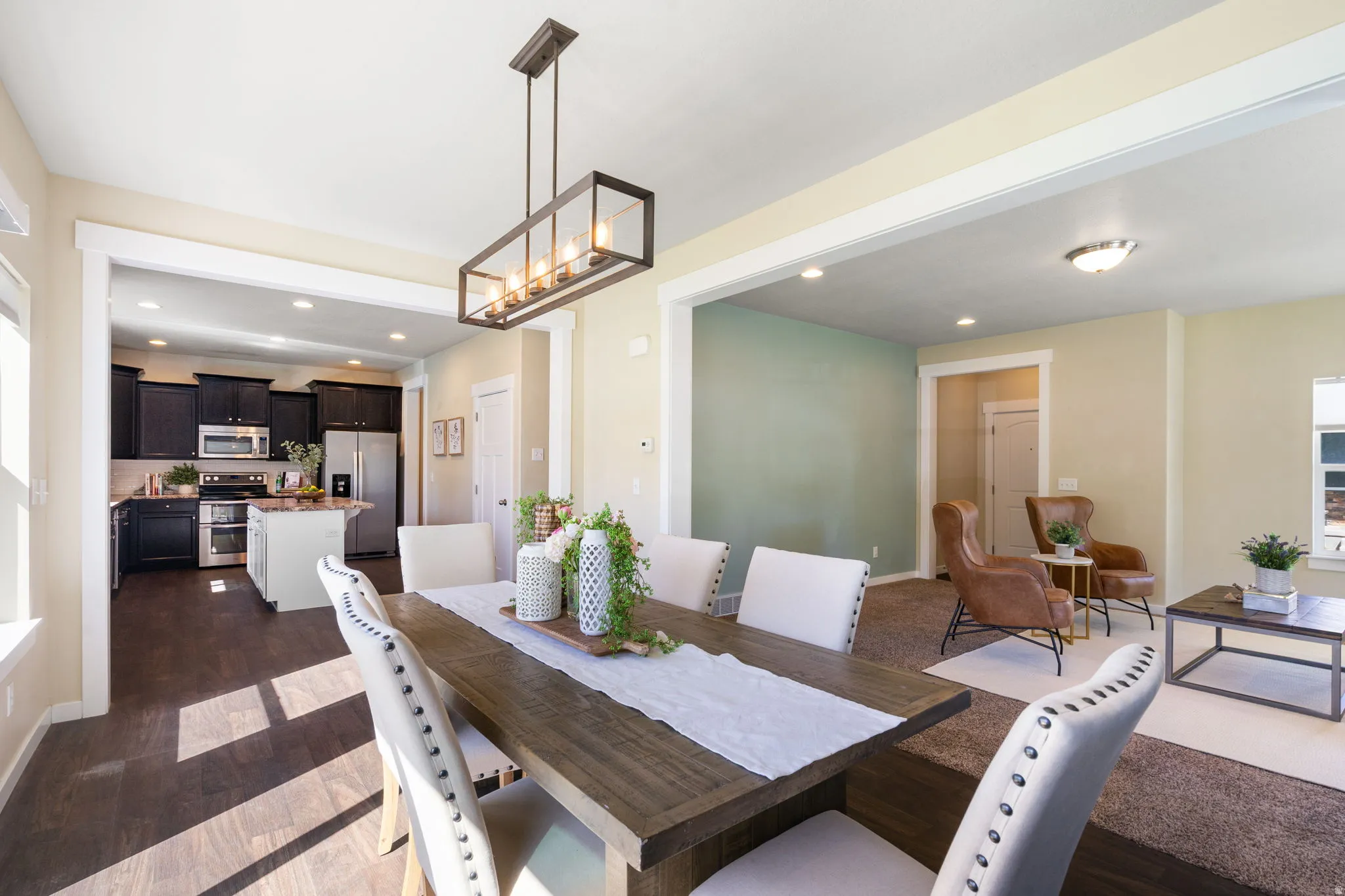 Dining area featuring a wood-finish table, upholstered chairs with nailhead trim, and a linear chandelier