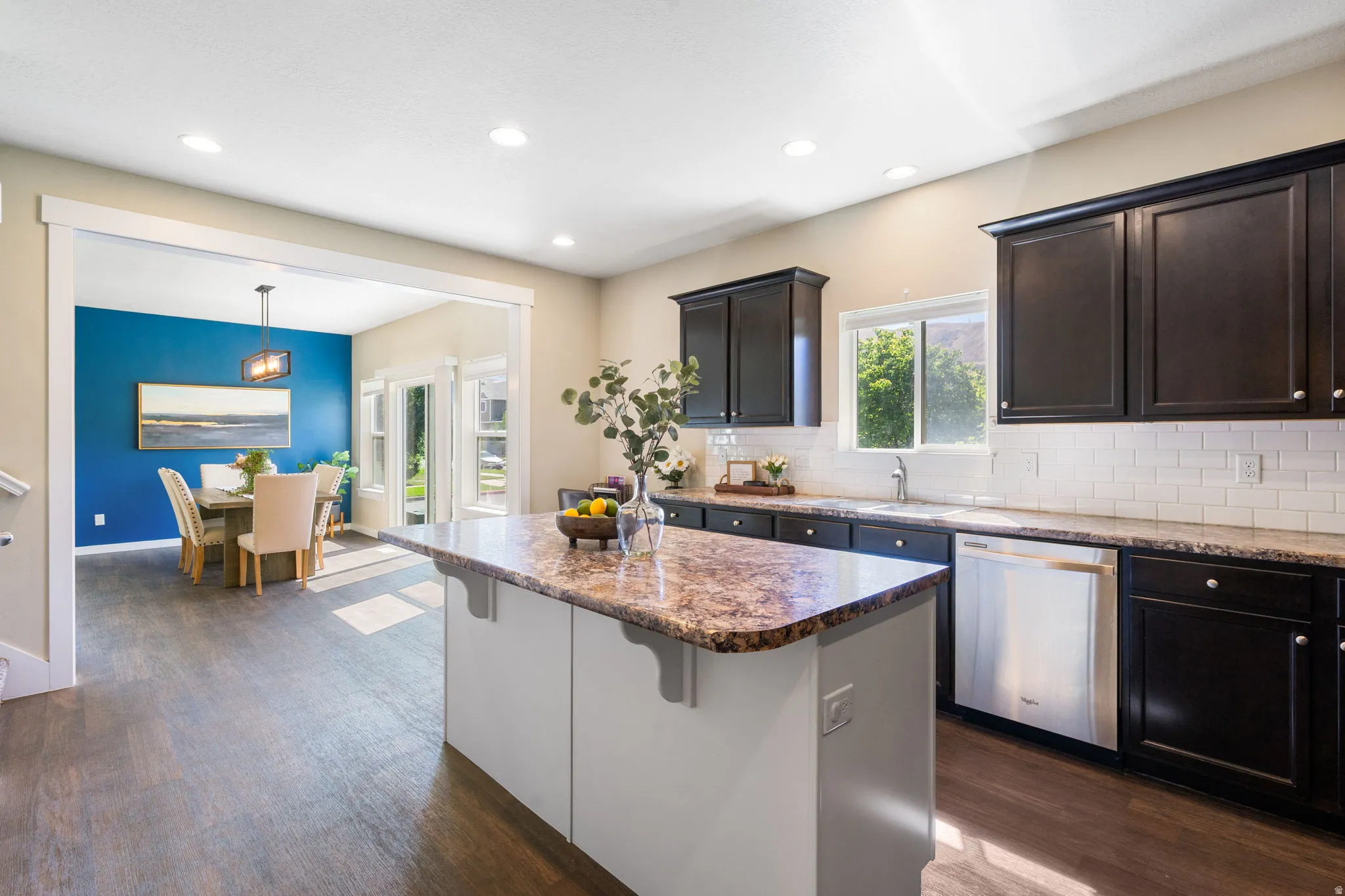 Kitchen featuring dark wood-finish cabinetry, a patterned countertop, and a white subway tile backsplash