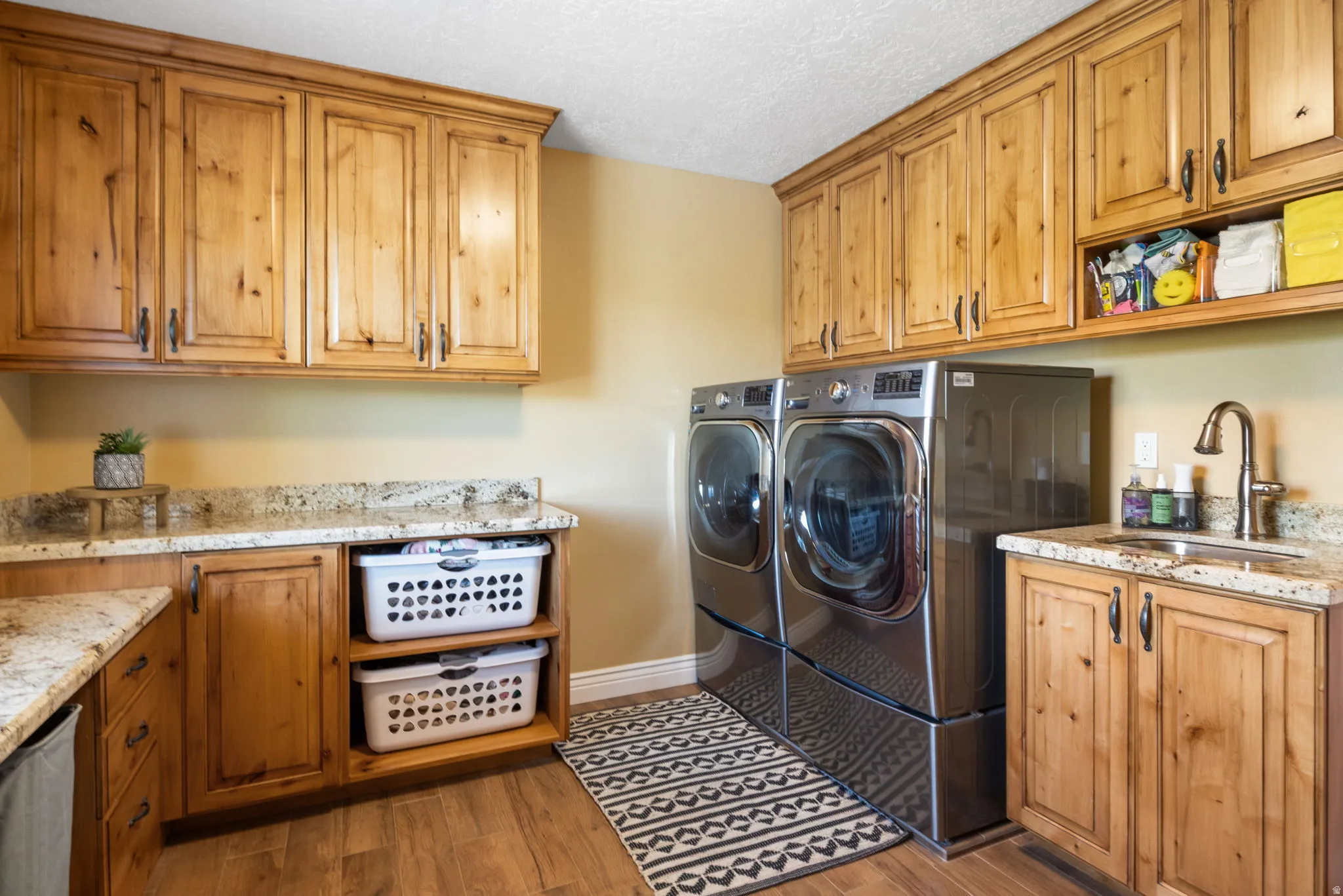 Laundry room with ample custom cabinetry, granite countertops, and a utility sink.