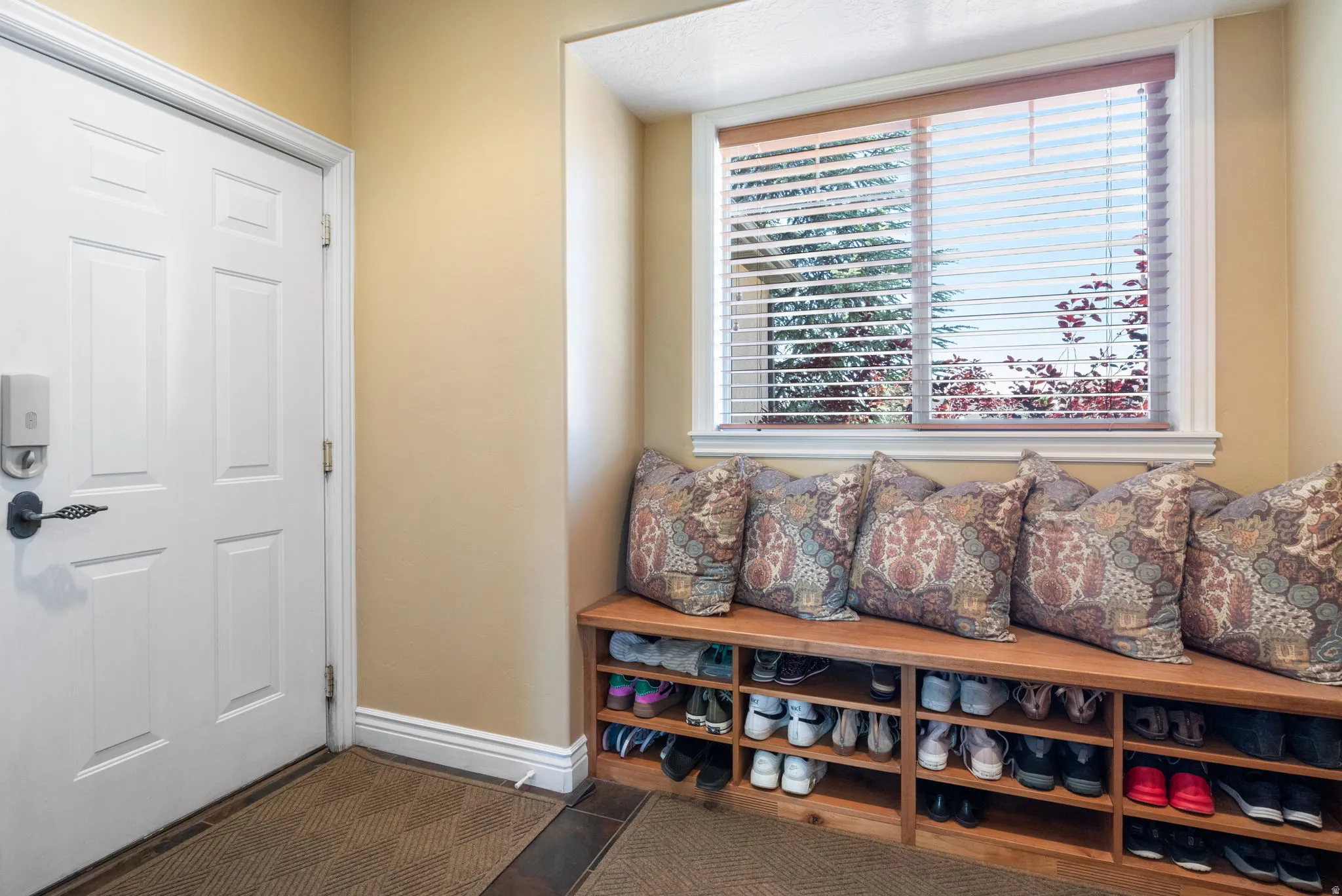 Custom built-in wood bench with integrated shoe storage in the garage entrance.
