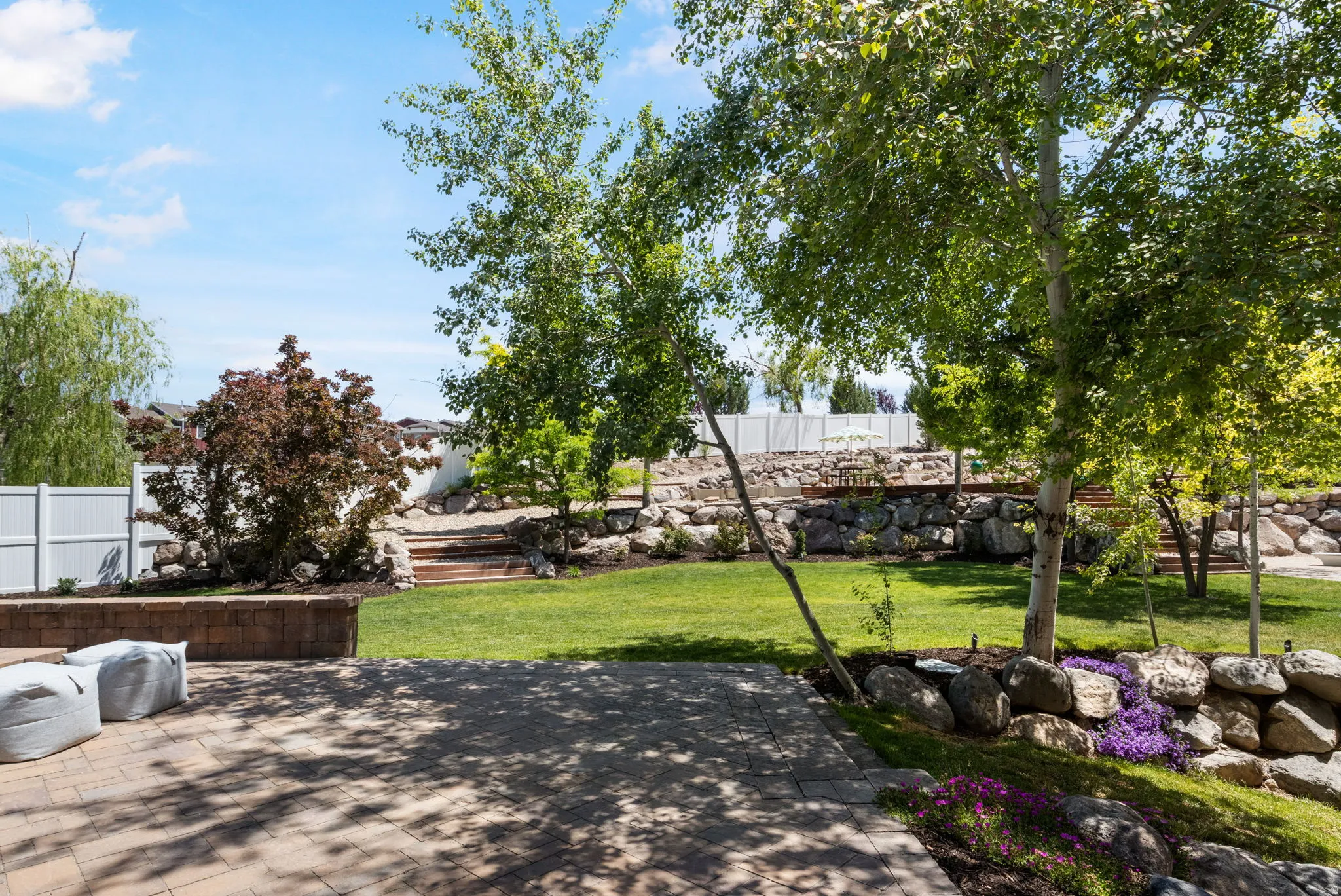 Expansive backyard featuring a paver patio with a brick retaining wall