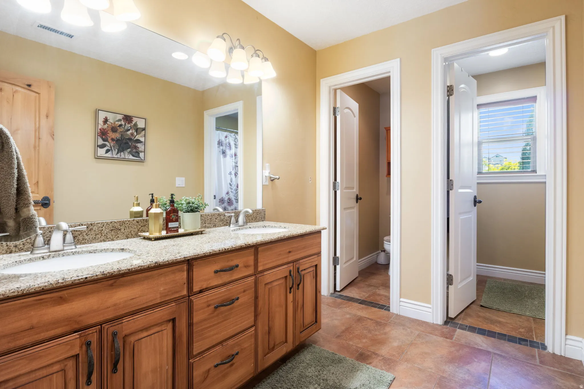 Shared hall bathroom has dual vanities and convenient separate shower and toilet rooms.