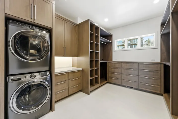 Dedicated laundry area with stacked appliances, complemented by extensive built-in cabinetry and drawers