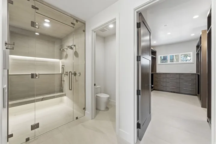 Glass-enclosed shower with a built-in bench, dual shower heads, and an integrated illuminated niche