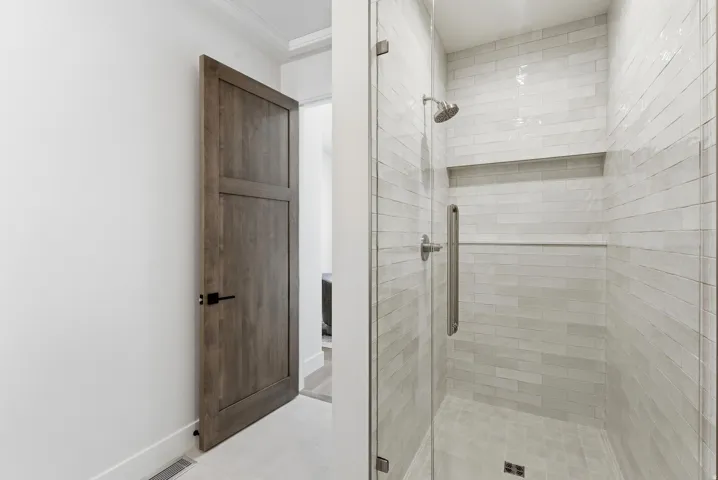 Walk-in shower featuring subway tile surround, recessed shelf, glass enclosure, and brushed nickel fixtures