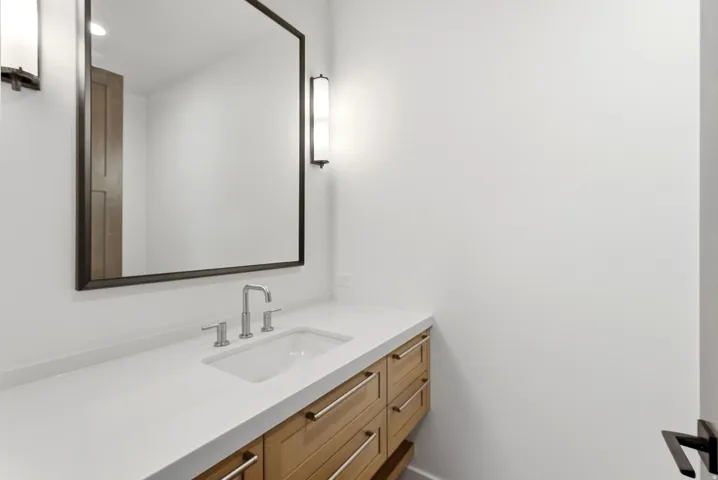 Contemporary bathroom vanity featuring a light wood finish, integrated sink, and brushed nickel hardware