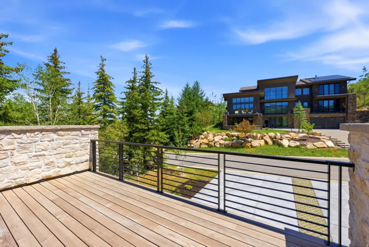 Expansive outdoor deck featuring wood-finish flooring and a contemporary metal railing system