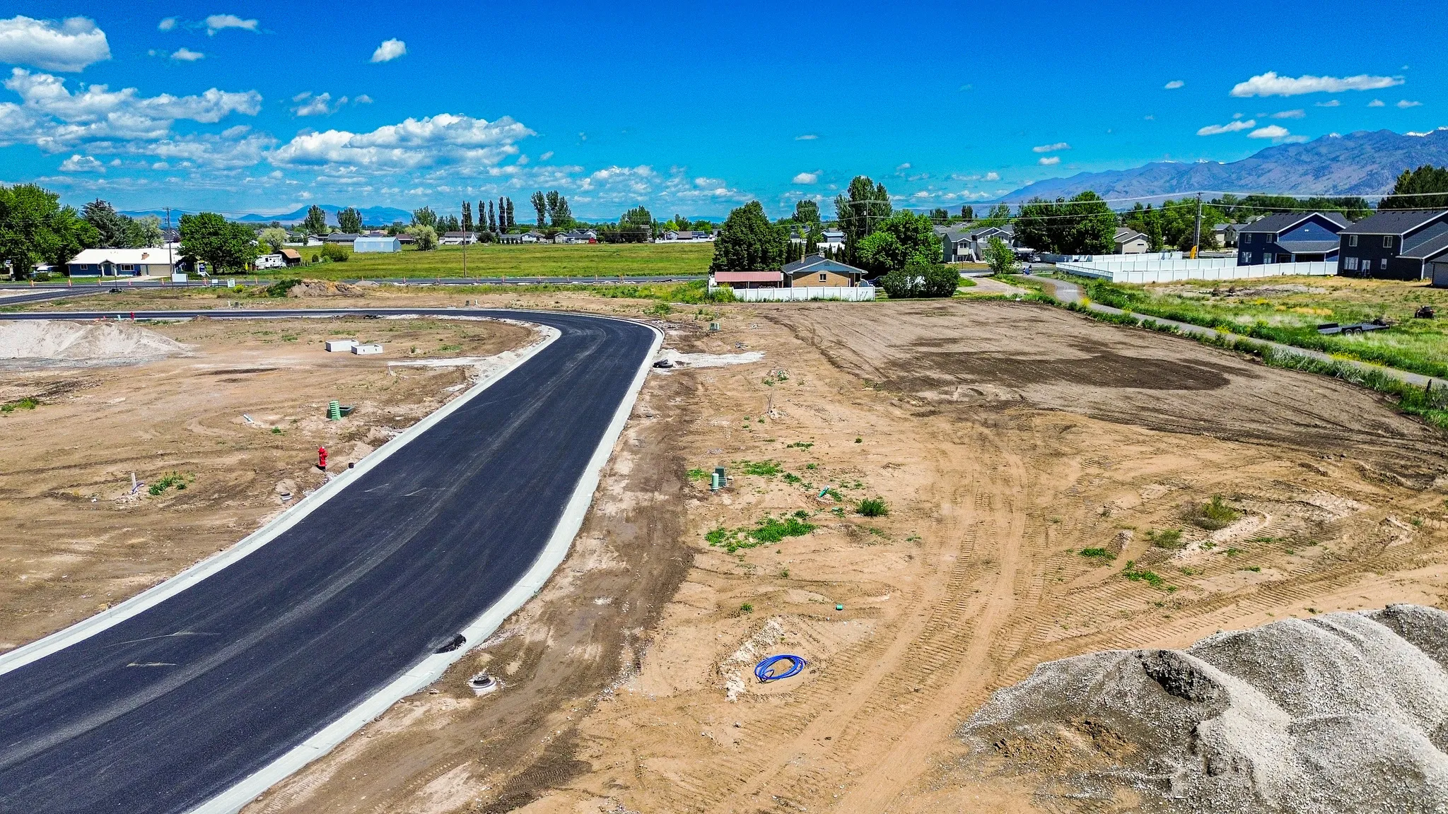 Paved road with curbing, surrounded by undeveloped land
