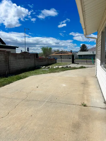 Concrete driveway with integrated curb, bordered by a block privacy wall and a grassy area