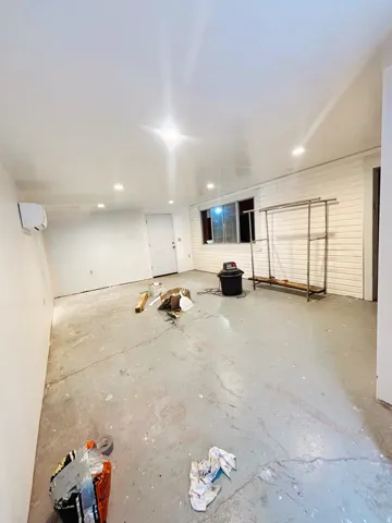 Spacious room featuring white painted walls and a concrete floor