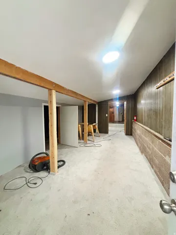 Spacious interior area featuring exposed wood framing, concrete flooring, and a flat white ceiling with recessed lighting