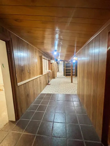 Hallway featuring wood paneling on walls and ceiling