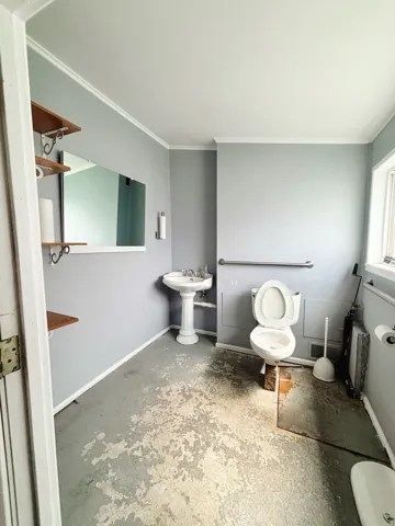 Pedestal sink with chrome fixtures, wall-mounted mirror, and wood shelving