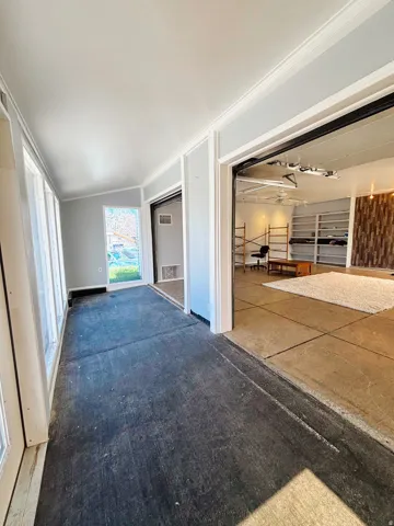 Sunroom with abundant natural light, crown molding, and direct access to an adjacent space featuring built-in shelving and a decorative wood wall accent