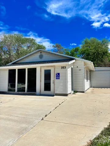 White siding structure with a prominent glass storefront entrance