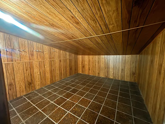 Space featuring wood-finish wall paneling, a wood-finish sloped ceiling, and square floor tiles with light grout