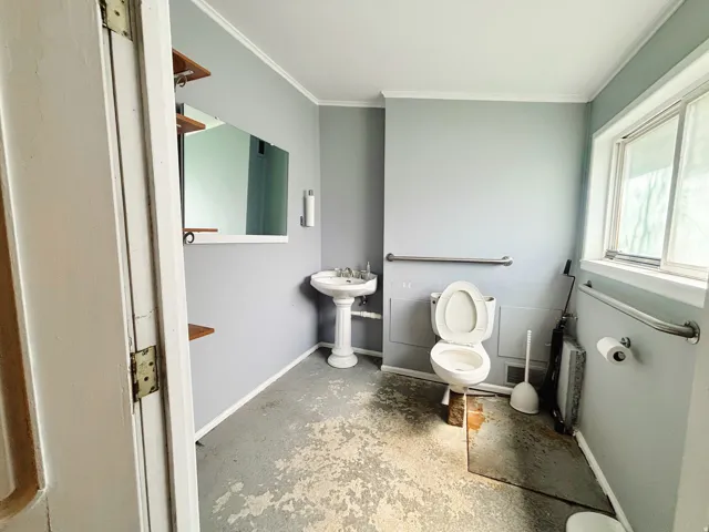 Pedestal sink with chrome fixtures, wall-mounted mirror, and wood shelving