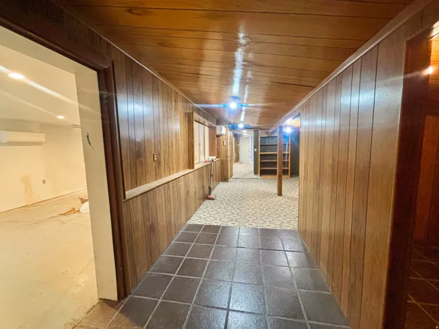 Hallway featuring wood-finish paneling, a wood-finish ceiling, and recessed lighting