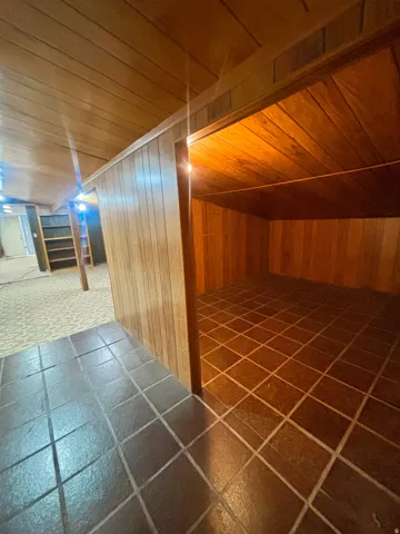 Interior space featuring horizontal wood paneling, a tiled floor, and a built-in shelving unit
