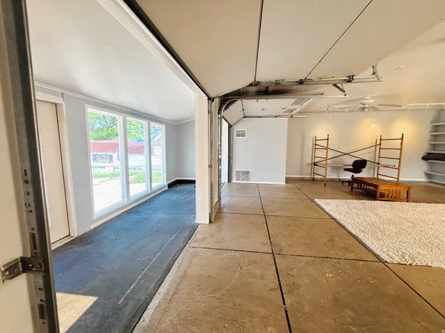 Spacious converted garage featuring a segmented concrete floor, built-in shelving, and a ceiling fan