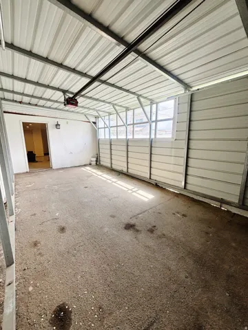 Carport featuring a corrugated metal roof, concrete flooring, and an automatic garage door opener