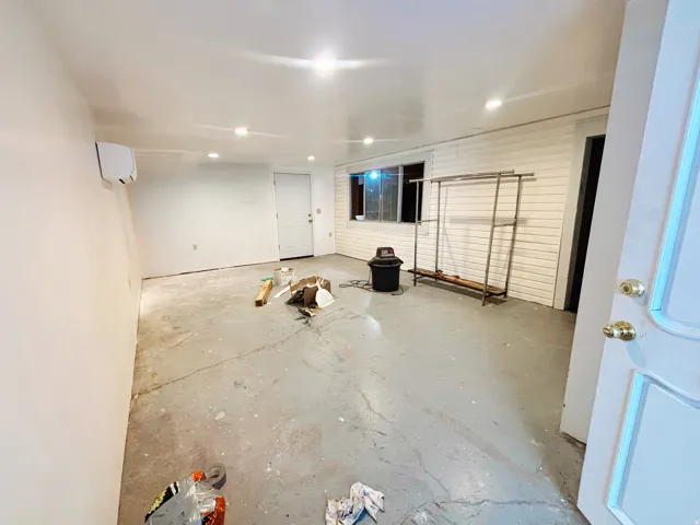 Spacious room featuring a smooth white ceiling with recessed lighting, white walls, and a concrete floor