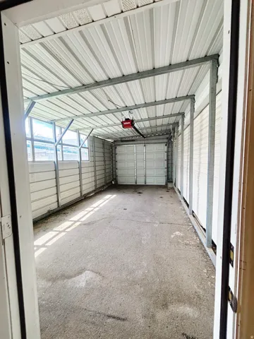 Covered outdoor structure featuring a concrete floor, corrugated metal siding, and a white metal roof