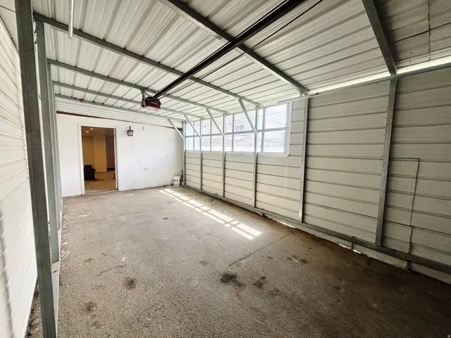 Carport featuring a metal roof, concrete flooring, and an integrated garage door opener