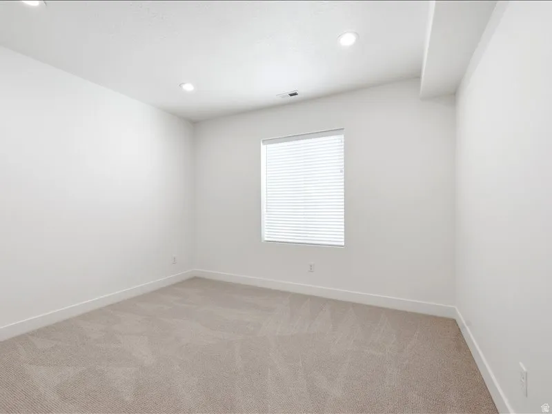 Bright room featuring light neutral carpeting and crisp white walls