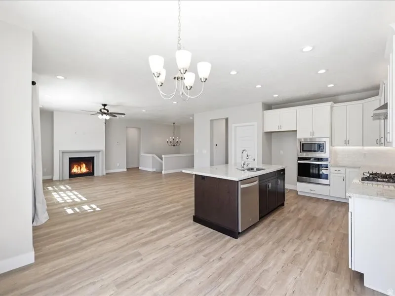 Open-concept living space featuring wood-finish flooring, a contemporary fireplace, and recessed lighting