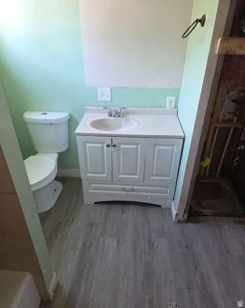 Bathroom featuring a white vanity with integrated sink, chrome faucet, and wood-finish flooring