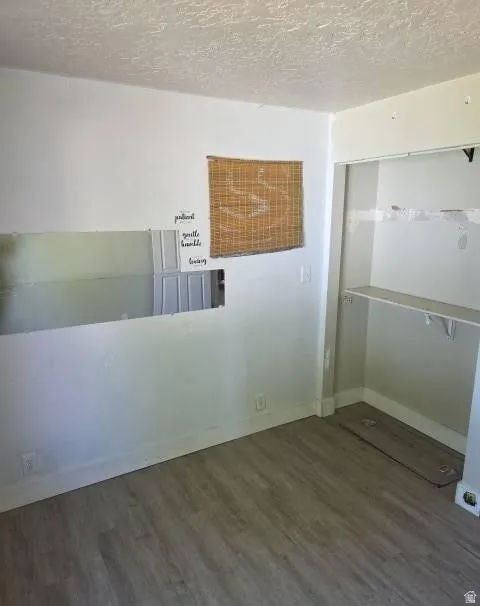 Room featuring wood-finish flooring, white baseboards, and a built-in closet with shelving