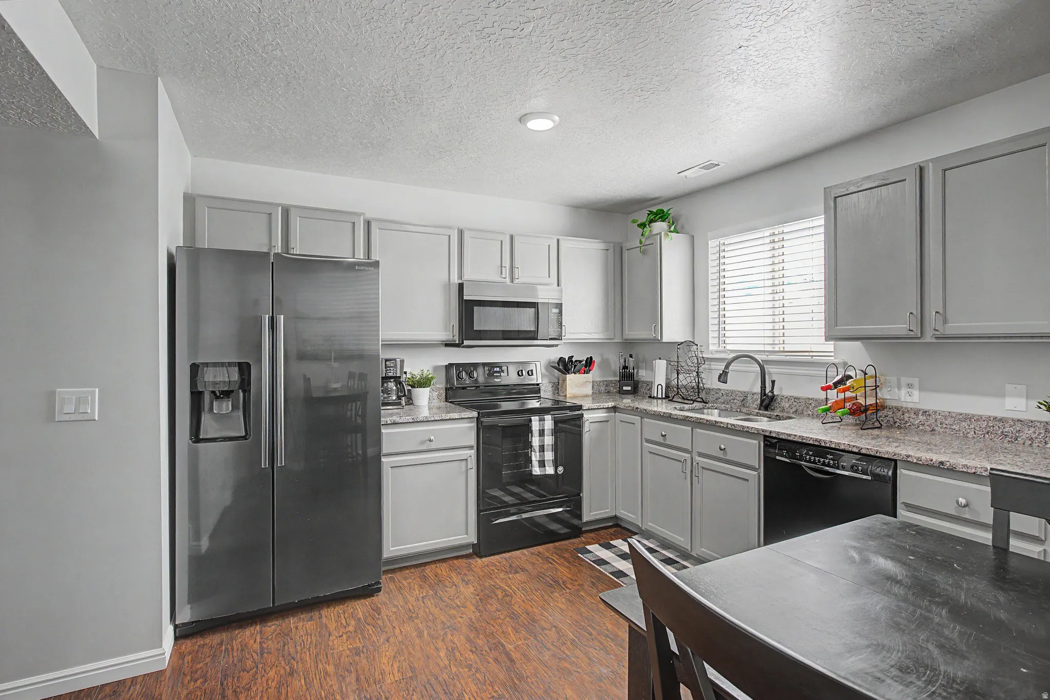 Kitchen featuring wood-finish flooring, light gray cabinetry, and dark countertops