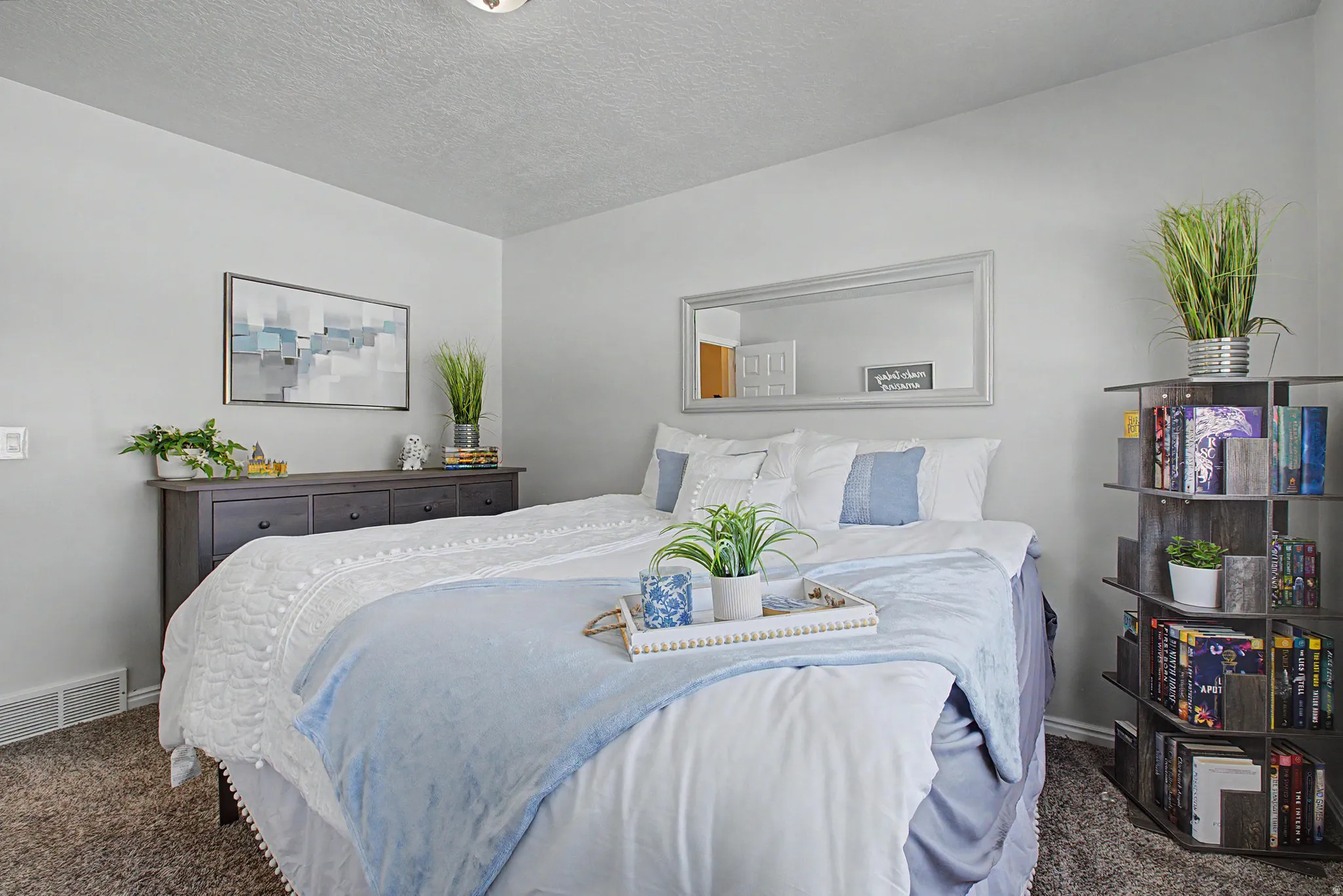 Carpeted bedroom featuring light gray walls, a built-in ceiling light, and a horizontal wall mirror