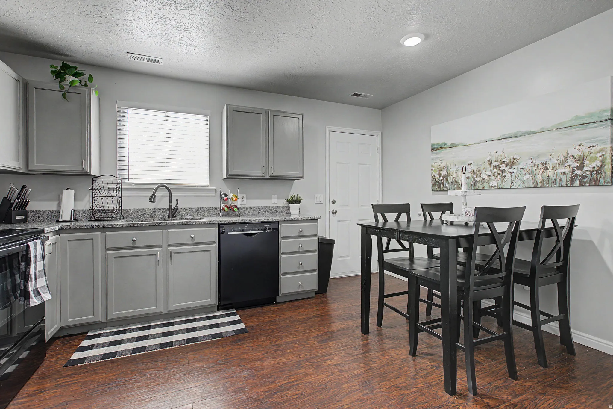 Kitchen featuring light gray cabinetry, speckled countertops, a dark finish sink faucet, and wood-finish flooring