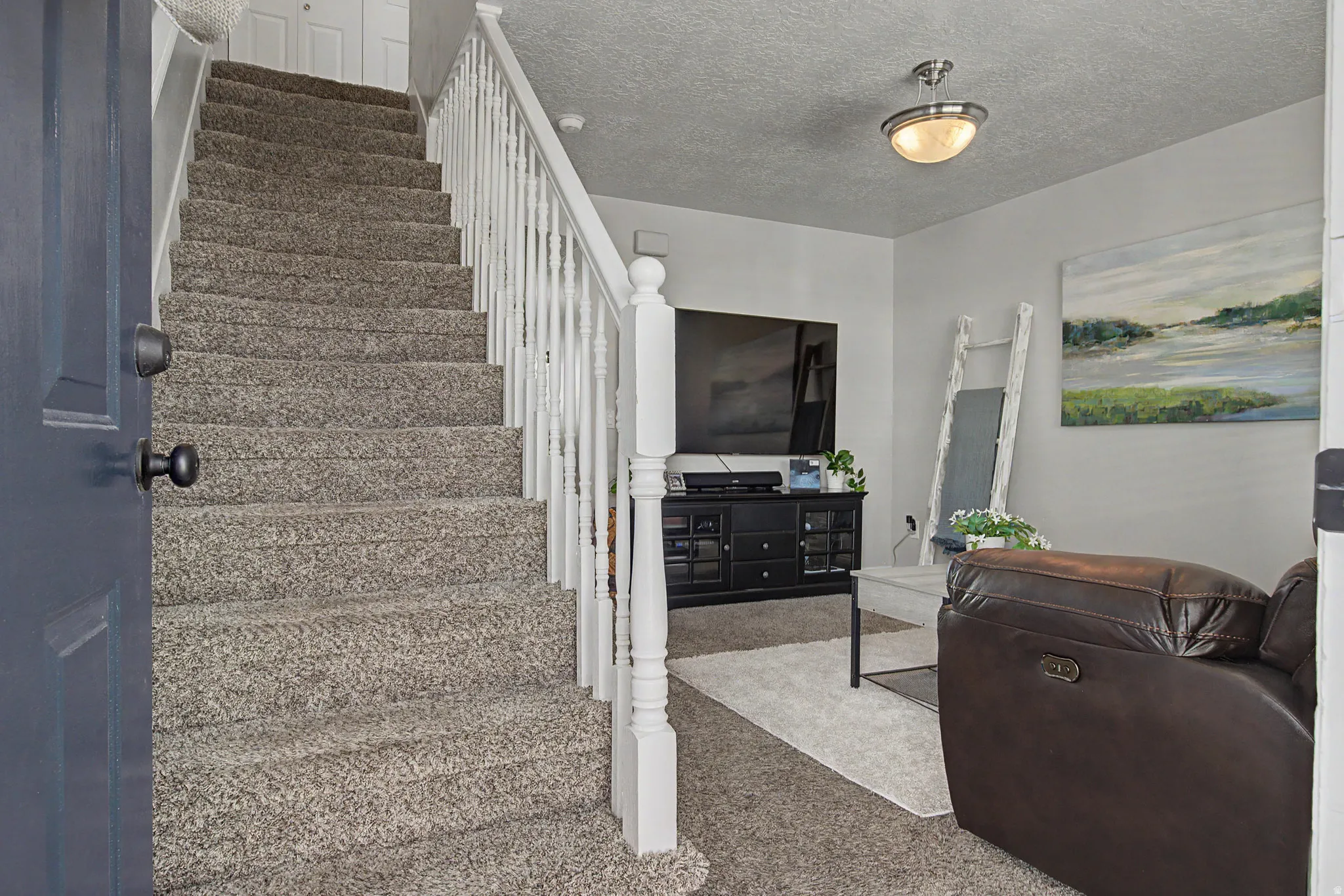 Entryway featuring a carpeted staircase with white balusters