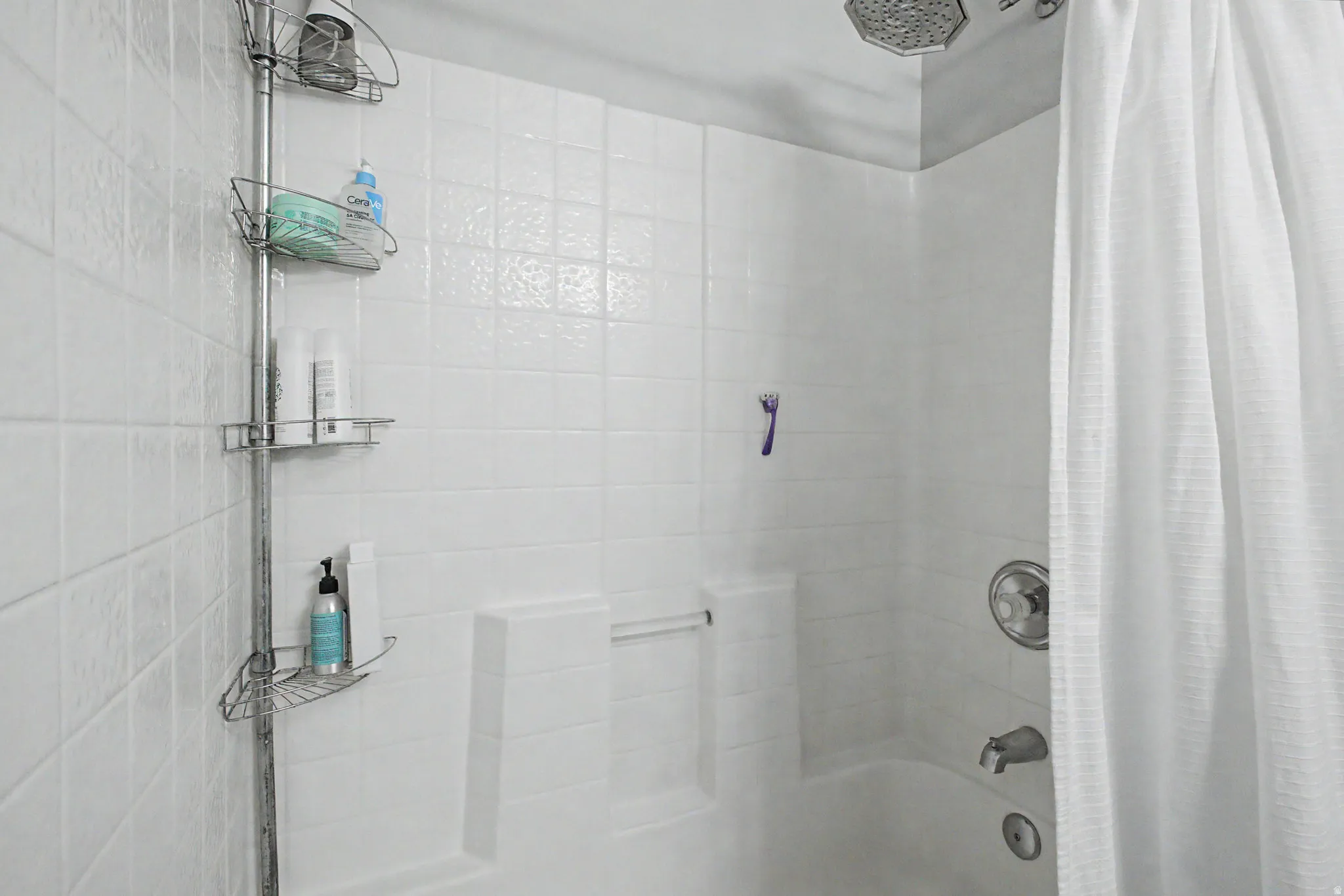 Bathtub with white tile surround and a chrome shower fixture