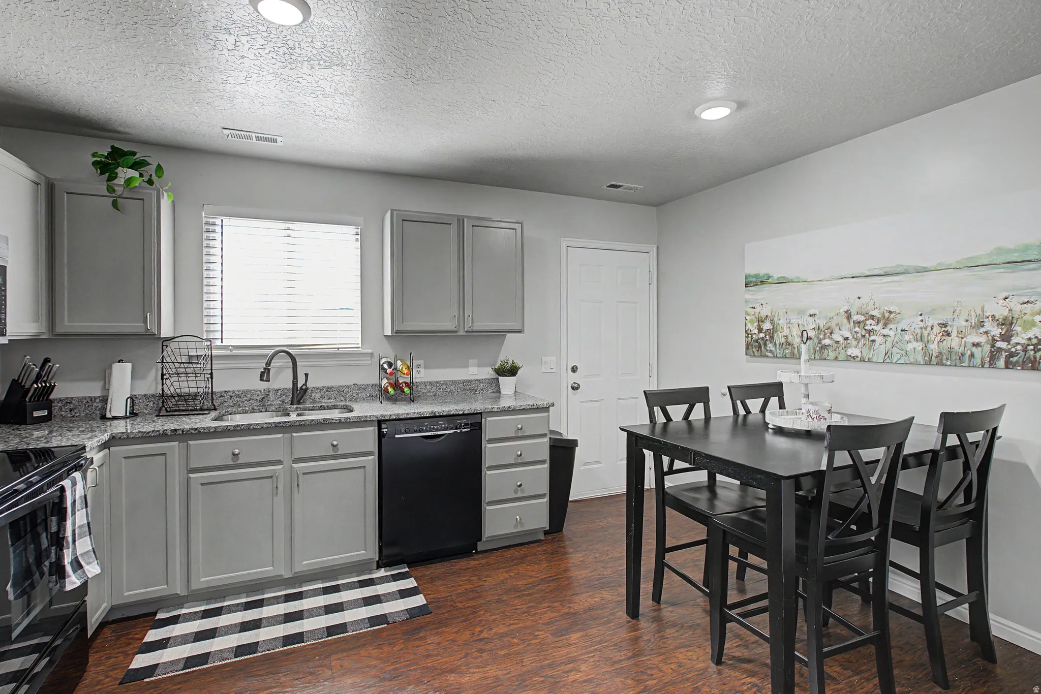 Modern kitchen featuring grey cabinetry, granite-style countertops, and wood-finish flooring