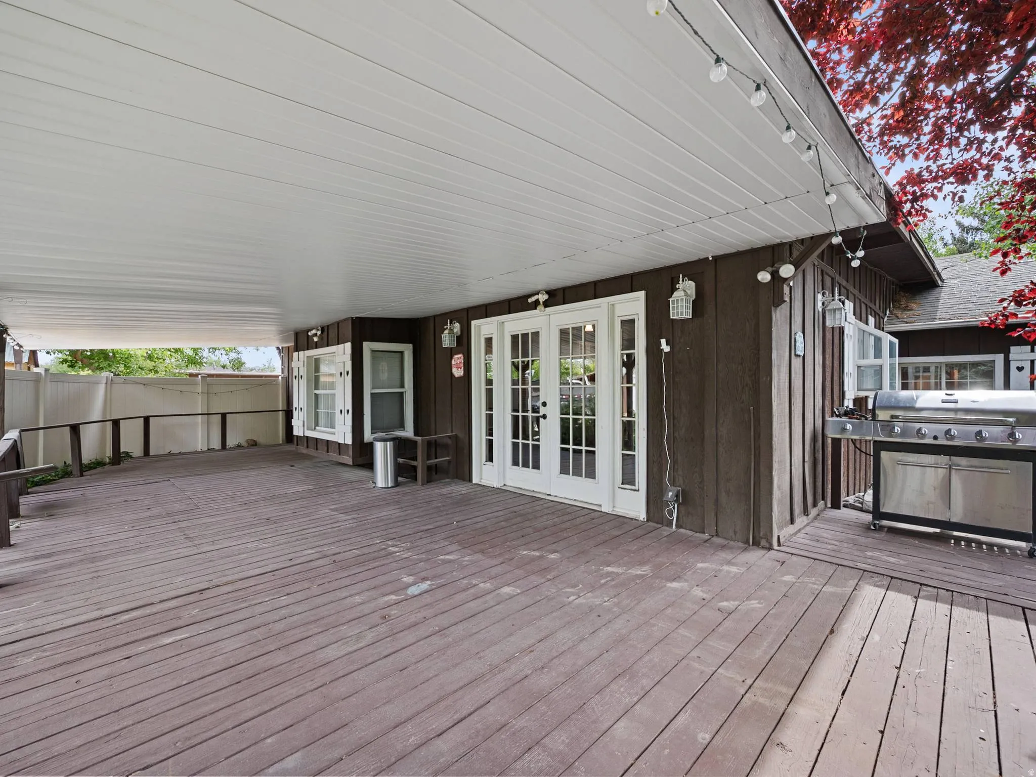 Expansive covered deck featuring wood decking, and white French doors