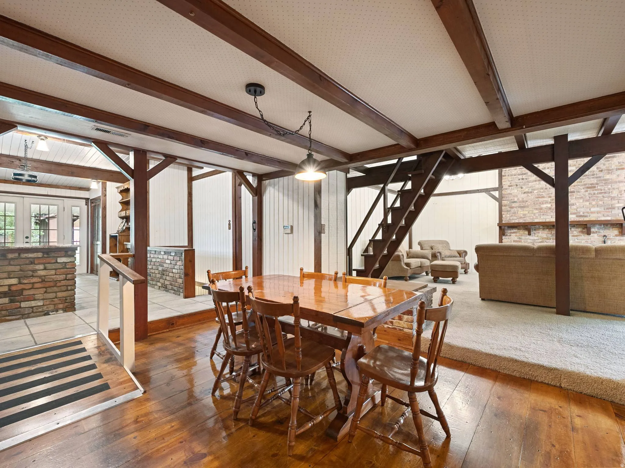 Open-concept dining area with wood-finish flooring, and exposed beams.