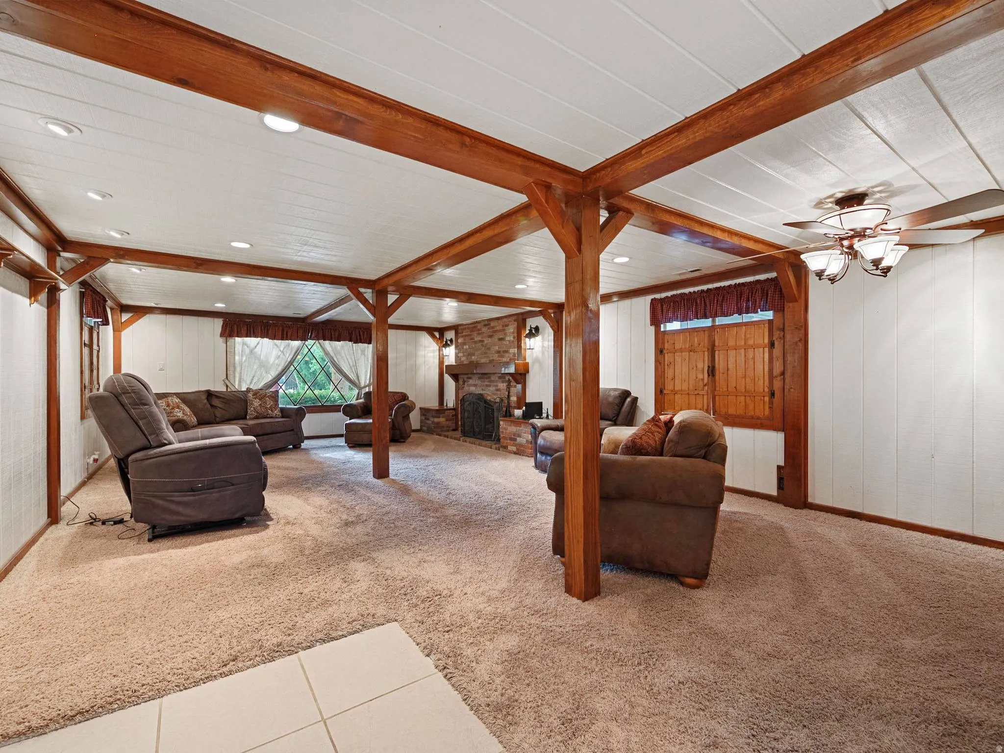 Spacious main level family room featuring exposed wood beams, a brick fireplace, and recessed lighting.