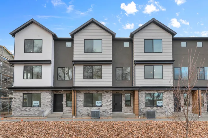 Contemporary townhome exteriors featuring varied siding, dark trim accents, and ground-level brickwork