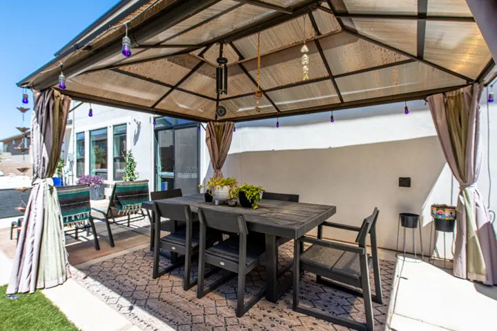 Covered patio featuring a solid roof structure with integrated lighting, concrete flooring, and a patterned outdoor rug