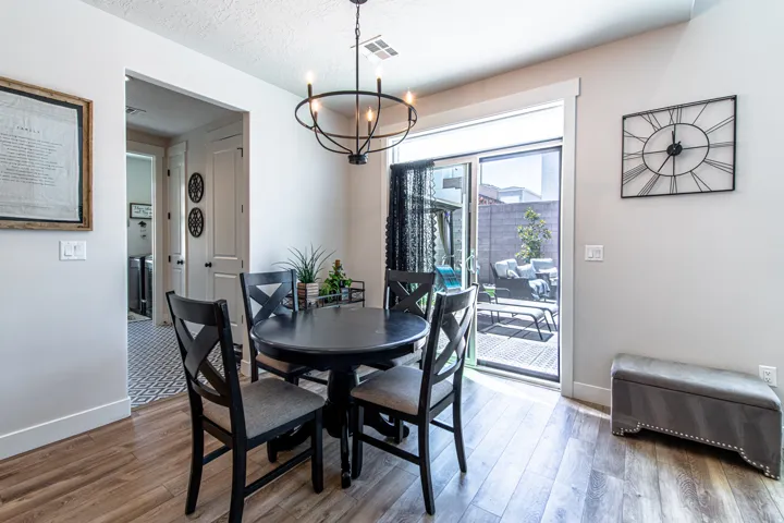 Dining area featuring wood-finish flooring, a contemporary chandelier, and a sliding glass door providing access to an outdoor patio with hardscaping