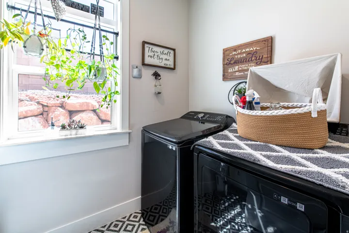 Laundry area featuring a window with white trim, light-toned walls, and dark-finish appliances